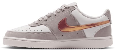 Fehér sportcipő szürke velúr elemekkel és arany Nike logóval. Fehér sportcipő szürke velúr elemekkel és arany Nike logóval.