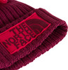 Eine rote Strickmütze mit The North Face Logo und Bommel.