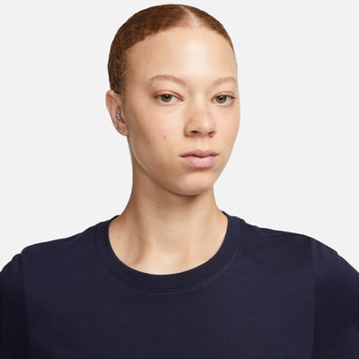 Eine Frau mit kurzen Haaren und Ohrringen in einem dunkelblauen T-Shirt. Eine Frau mit kurzen Haaren und Ohrringen in einem dunkelblauen T-Shirt.