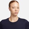 Eine Frau mit kurzen Haaren und Ohrringen in einem dunkelblauen T-Shirt.