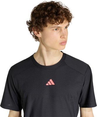 Herren-T-Shirt von Adidas in Schwarz mit rosa Logo auf der Brust.