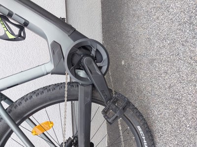 Teil eines E-Bikes mit Kurbel, Kette und Pedal an der Wand.