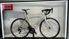 Ein weißes Simplon Rennrad mit Schriftzug auf dem Rahmen im Geschäft.