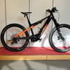 Schwarzes KTM E-Mountainbike mit orangefarbenen Akzenten auf rotem Teppich.