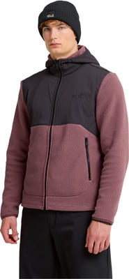 Ein Mann in schwarzer Mütze und rosa Fleecejacke mit schwarzer Kapuze.