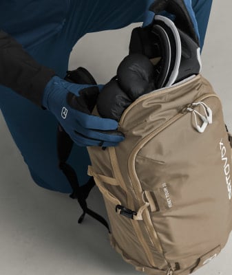 Person in blauen Handschuhen verstaut Skibrille und Handschuhe in einem Rucksack. Person in blauen Handschuhen verstaut Skibrille und Handschuhe in einem Rucksack.