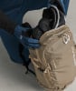 Person in blauen Handschuhen verstaut Skibrille und Handschuhe in einem Rucksack.