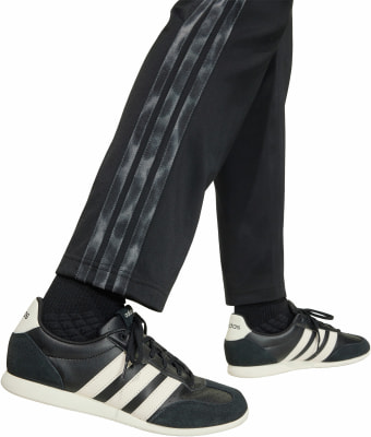 Schwarze Sporthose mit Streifen und Adidas-Sneakers für Herren. Schwarze Sporthose mit Streifen und Adidas-Sneakers für Herren.
