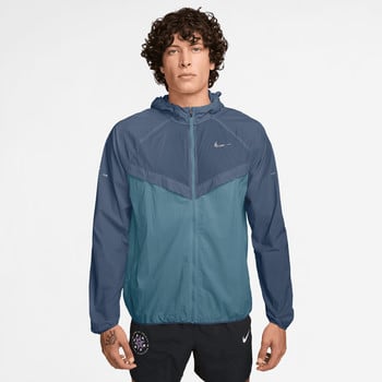Mann in einer blauen Kapuzenjacke und schwarzen Shorts mit Nike-Logo.
