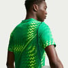 Mann in einem grünen T-Shirt mit geometrischem Muster, von hinten gesehen.