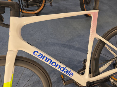 Ein weißes Cannondale Rennrad mit blauem Logo und rotem Muster. Ein weißes Cannondale Rennrad mit blauem Logo und rotem Muster.