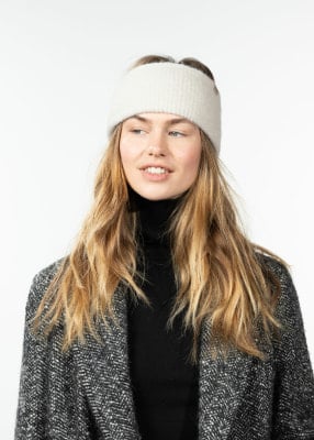 Eine Frau mit blonden Haaren trägt ein weißes Stirnband und einen schwarzen Rollkragenpullover. Eine Frau mit blonden Haaren trägt ein weißes Stirnband und einen schwarzen Rollkragenpullover.