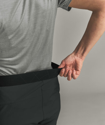 Ein Mann zieht seine dunkle Hose am Bund herunter und zeigt das Gummiband. Ein Mann zieht seine dunkle Hose am Bund herunter und zeigt das Gummiband.