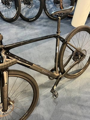 Ein schwarzes Trek Gravelbike mit schwarzem Rahmen und Rädern auf blauem Teppich. Ein schwarzes Trek Gravelbike mit schwarzem Rahmen und Rädern auf blauem Teppich.