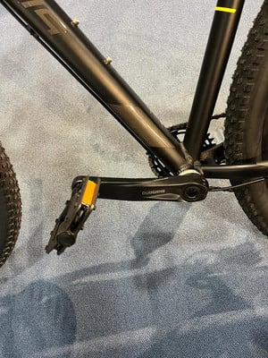 Detail eines schwarzen Fahrradrahmens mit Shimano-Pedal und teilweise sichtbarem Reifen. Detail eines schwarzen Fahrradrahmens mit Shimano-Pedal und teilweise sichtbarem Reifen.