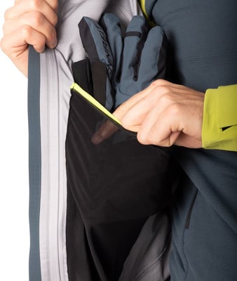 Ein Mann legt Handschuhe in eine Jackentasche mit neonfarbenem Besatz. Ein Mann legt Handschuhe in eine Jackentasche mit neonfarbenem Besatz.