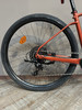 Hinterrad eines orangefarbenen Fahrrads mit Schaltwerk und Kette.