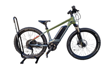 Grünes E-Bike auf einem Ständer vor weißem Hintergrund.