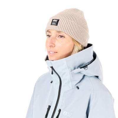 Eine Frau in einer beigen Mütze und einer hellblauen Jacke vor weißem Hintergrund. Eine Frau in einer beigen Mütze und einer hellblauen Jacke vor weißem Hintergrund.