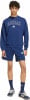 Ein Mann in einem blauen Adidas-Anzug mit Logo auf Sweatshirt und Shorts.