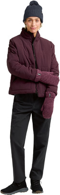 Frau in burgunderroter Jacke, schwarzer Hose und Strickmütze.