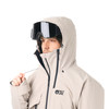 Ein Mann in einer beige Kapuzenjacke mit Skibrille blickt zur Seite.