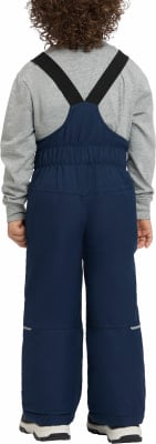Rückansicht eines Jungen in dunkelblauer Latzhose und grauem Oberteil.