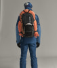 Ein Mann in blauer Jacke und Hose mit Rucksack und Seil auf dem Rücken.