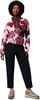 Eine Frau in einem bunten Fleece-Pullover und schwarzer Hose mit Schuhen.