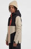 Junge in beiger Jacke mit schwarzen Einsätzen und orangefarbenem Reißverschluss und Mütze.