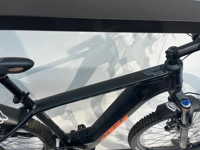 Schwarzes E-Mountainbike mit orangefarbenen Akzenten und Federung. Schwarzes E-Mountainbike mit orangefarbenen Akzenten und Federung.