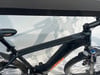 Schwarzes E-Mountainbike mit orangefarbenen Akzenten und Federung.