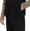 Mann in schwarzer Weste und braunem Pullover, Hand in der Tasche.