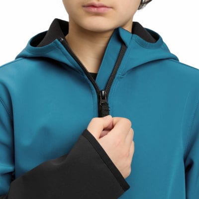 Ein Kind schließt eine blaue Jacke mit schwarzem Futter und Kapuze.