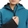 Ein Kind schließt eine blaue Jacke mit schwarzem Futter und Kapuze.