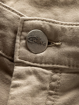 Detail eines Knopfes mit Markenlogo auf einer beigen Hose. Detail eines Knopfes mit Markenlogo auf einer beigen Hose.