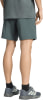 Ein Mann in dunkelgrünen Shorts und T-Shirt mit Turnschuhen und schwarzen Socken.