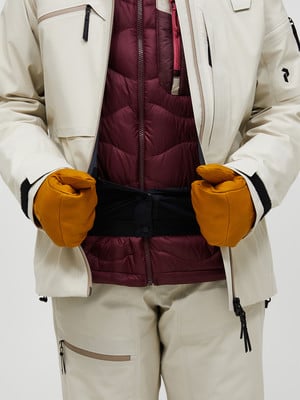 Person in beiger Jacke mit weinroter Weste und Handschuhen. Person in beiger Jacke mit weinroter Weste und Handschuhen.