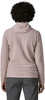 Rückansicht einer Frau mit lockigem Haar in einem rosa Pullover und einer grauen Hose.