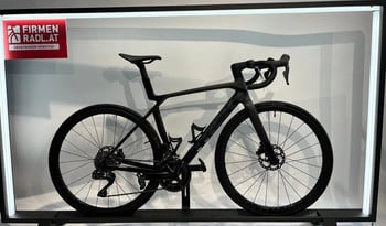 Ein schwarzes Trek Rennrad in einem beleuchteten Rahmen mit Firmenlogo.