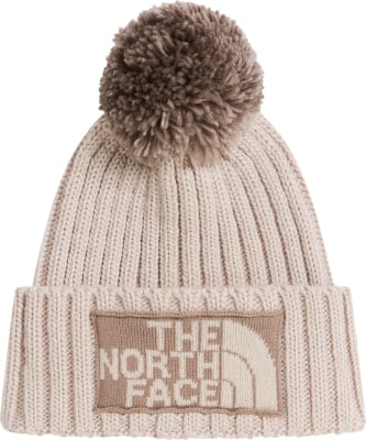 Eine beige Strickmütze mit Bommel und The North Face Logo. Eine beige Strickmütze mit Bommel und The North Face Logo.