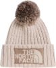 Eine beige Strickmütze mit Bommel und The North Face Logo.