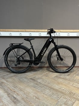Ein schwarzes Cube E-Bike steht auf einem Holzboden vor einer grauen Wand.