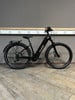 Ein schwarzes Cube E-Bike steht auf einem Holzboden vor einer grauen Wand.