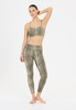 Ein Model in einem Leoparden-Top und Leggings posiert vor weißem Hintergrund.