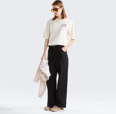 Eine Frau in einem cremefarbenen T-Shirt und schwarzer Hose hält einen Pullover. Eine Frau in einem cremefarbenen T-Shirt und schwarzer Hose hält einen Pullover.