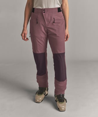 Frau in rosa Skihose und Skischuhen auf grauem Hintergrund. Frau in rosa Skihose und Skischuhen auf grauem Hintergrund.