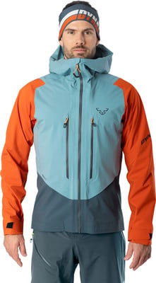 Ein Mann in einer blau-orangefarbenen Skijacke und einer Mütze mit Dynafit-Logo.