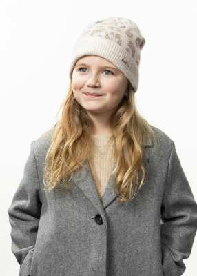 Ein Mädchen mit langen Haaren trägt einen grauen Mantel und eine beige Mütze mit Muster. Ein Mädchen mit langen Haaren trägt einen grauen Mantel und eine beige Mütze mit Muster.
