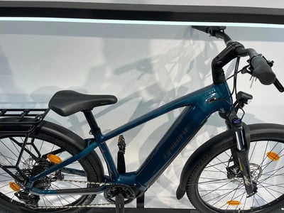 Ein blaugrünes Elektrofahrrad mit Gepäckträger und Frontlicht. Ein blaugrünes Elektrofahrrad mit Gepäckträger und Frontlicht.